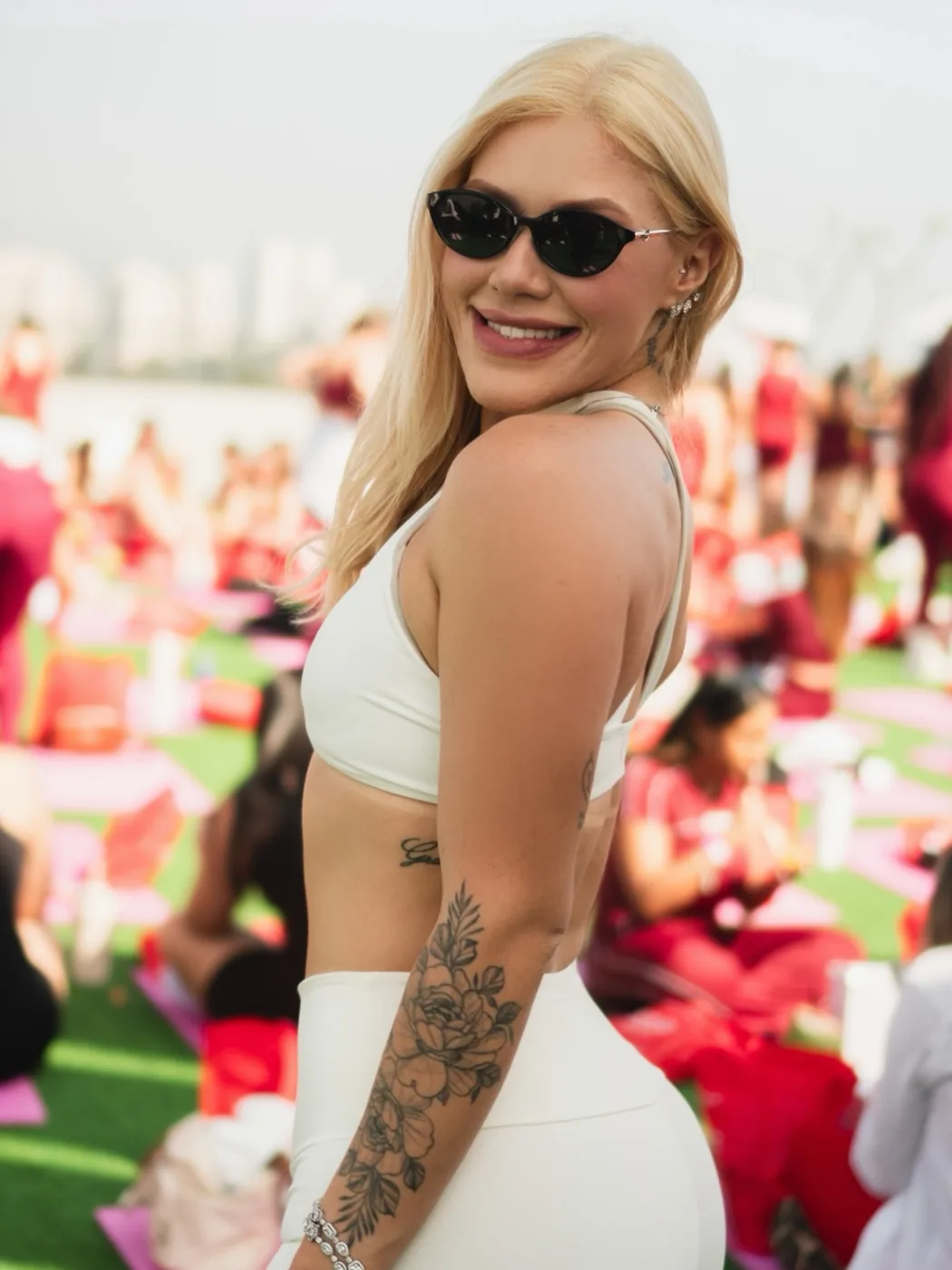 Bre Cardoso de óculos escuros e top branco, sorrindo durante a LOOUE Red Edition