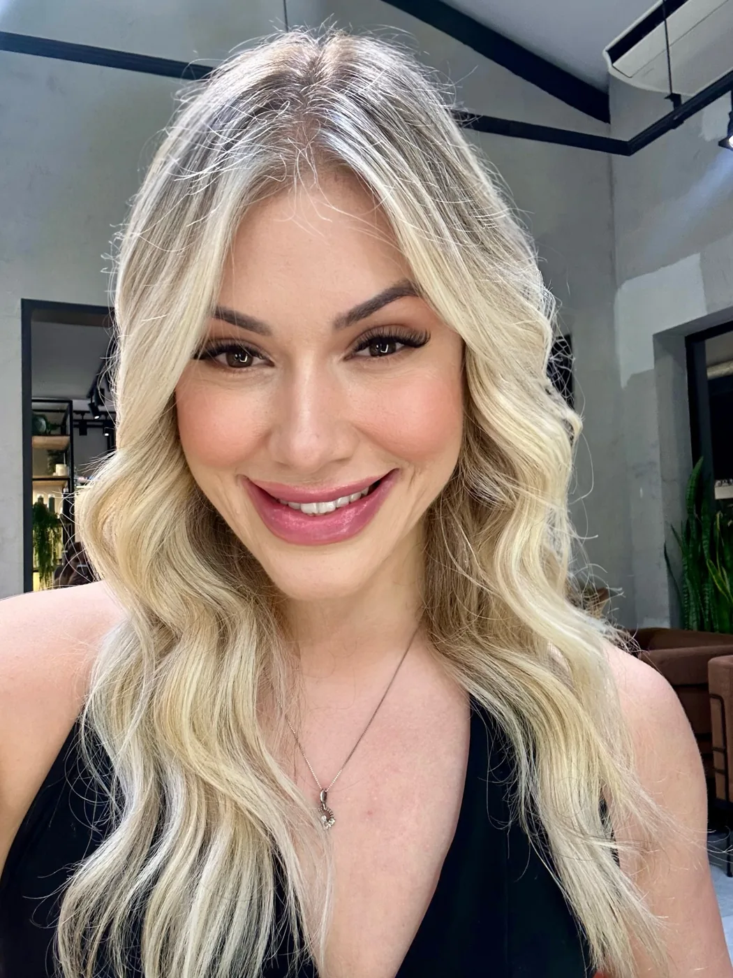 Bre Cardoso sorrindo, de blusa preta e cabelo loiro solto